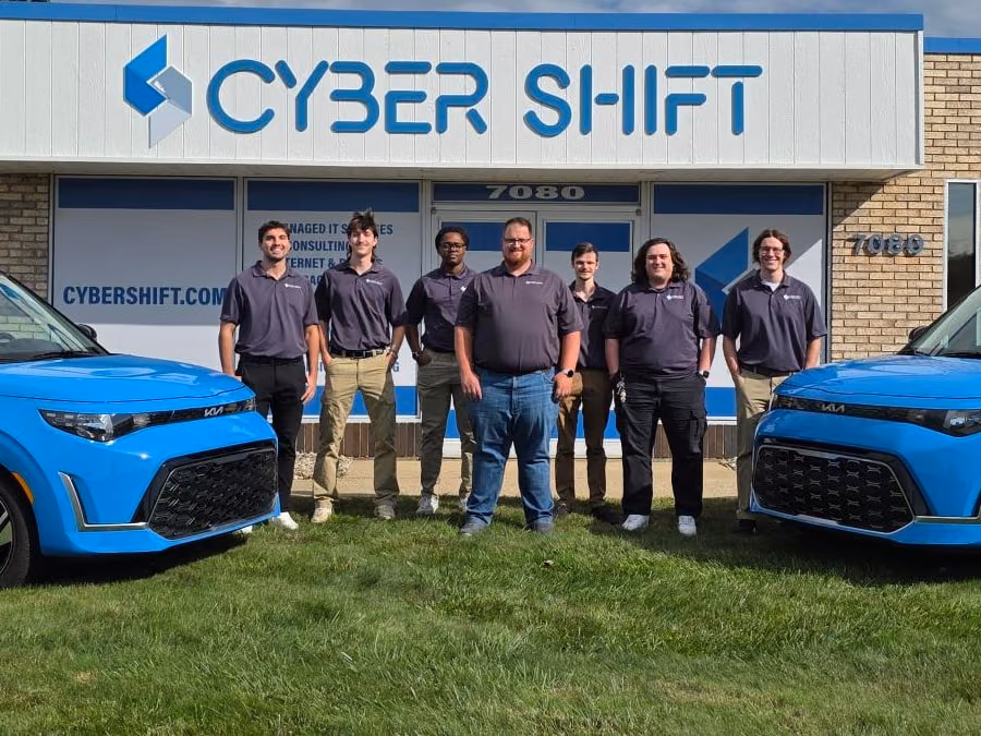 The Cyber Shift team standing outside the North Canton office between two blue Cyber Shift vehicles. The Cyber Shift team standing outside the North Canton office between two blue Cyber Shift vehicles.